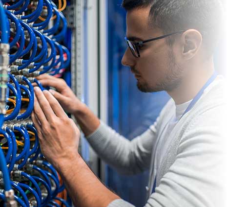 man connecting wires in server cabinet while working with supercomputer in data center