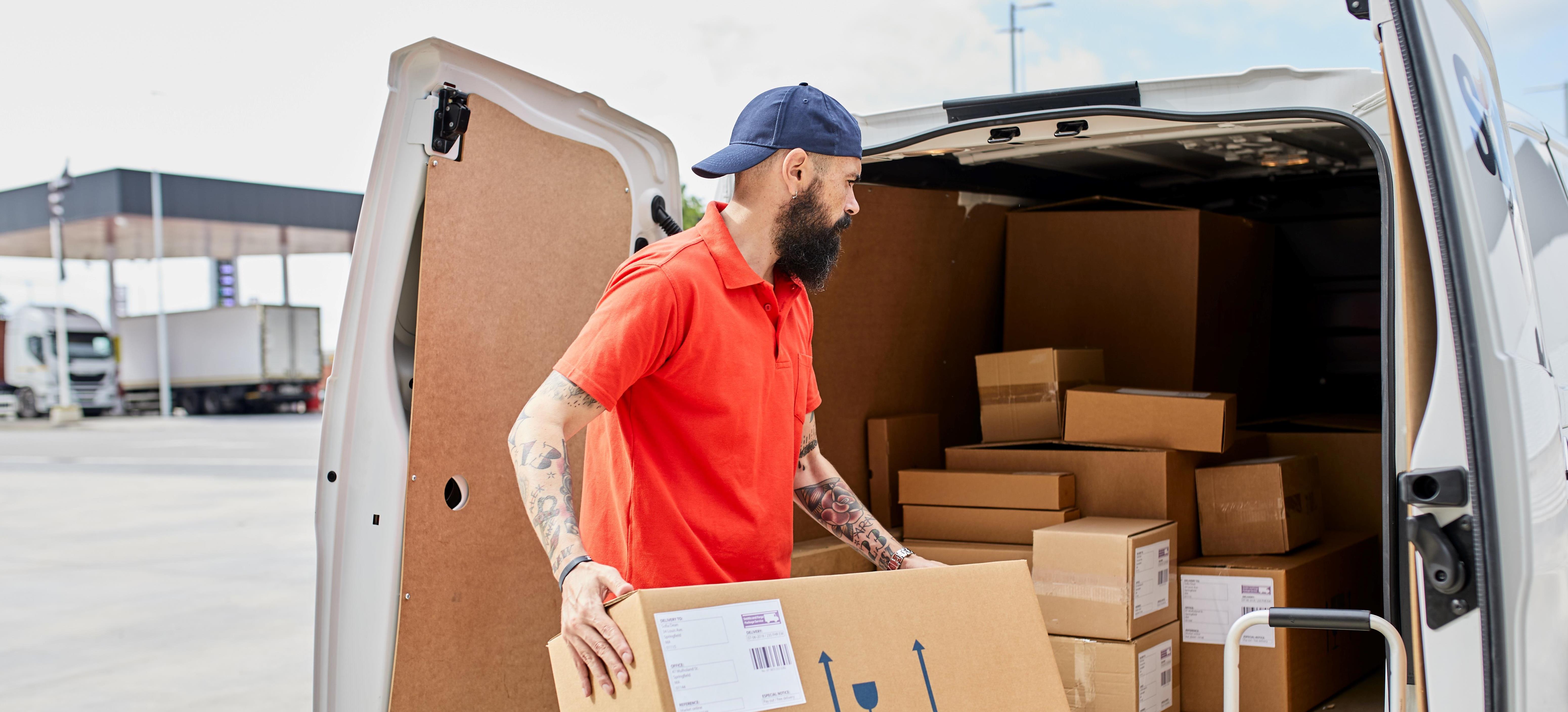 Man fills his van with boxes for his delivery route.