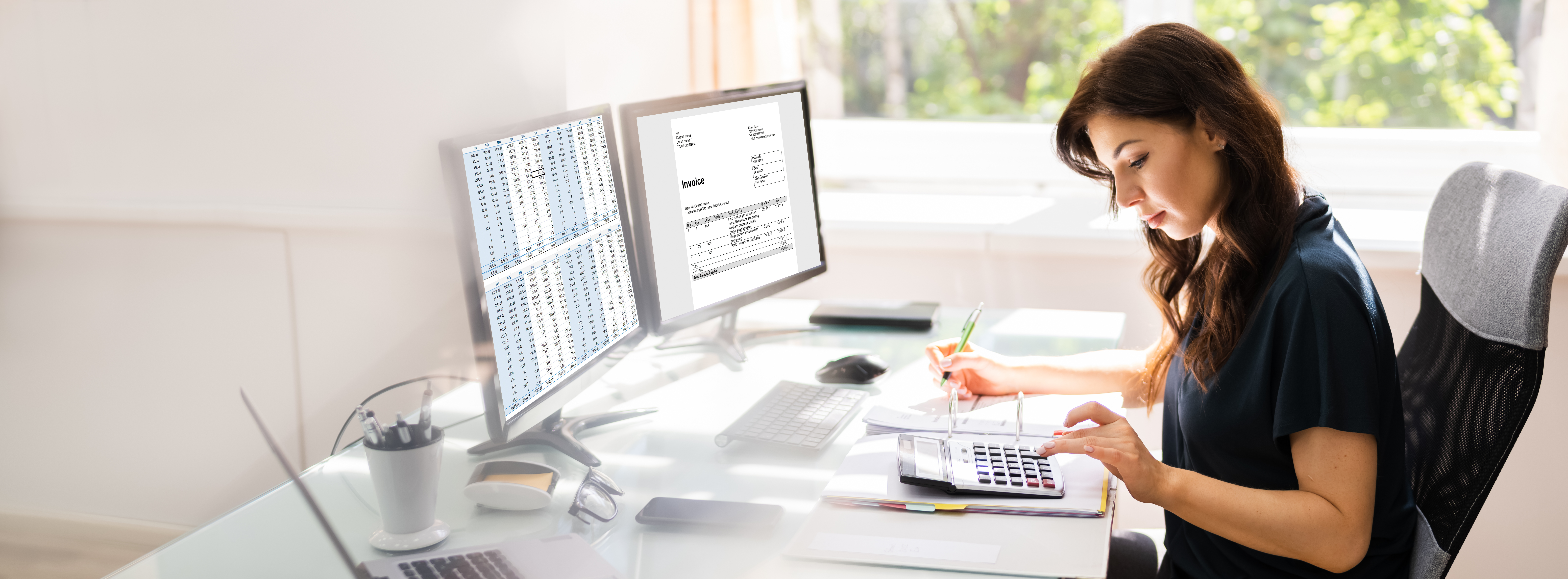 Business woman working on a computer and a calculator at a desk